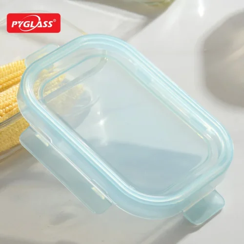 Blue rectangular glass food storage container with an airtight lid placed on a light-colored surface.