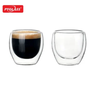Two double wall glass tumblers, one filled with espresso and the other empty, in a clean design with Pyglass branding.