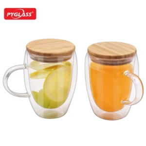 Two double-wall glass mugs with bamboo lids, one filled with lemon slices and water, the other with orange juice.