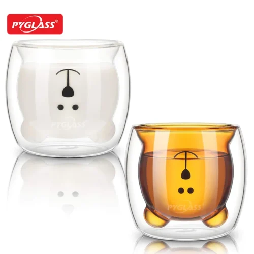 Two double-walled glass cups featuring adorable bear designs, one with milk and the other with tea. High-quality PYGLASS branding is visible.