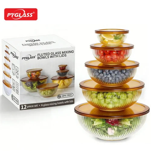 Stacked fluted glass mixing bowls with amber lids in various sizes beside product packaging, showing fresh produce inside.