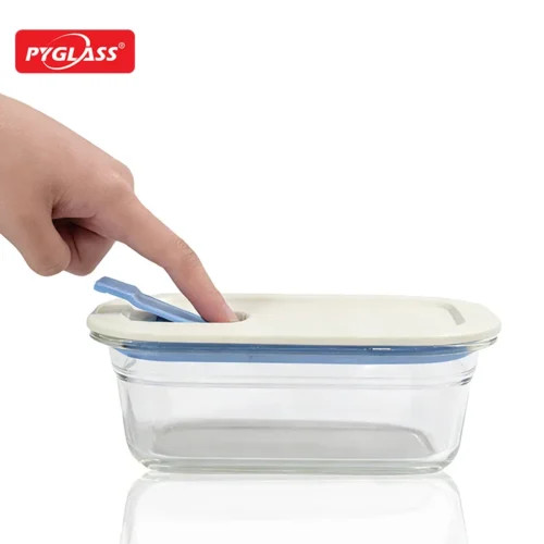 A hand pressing down on the lid of a glass container with a blue and cream sealing mechanism.