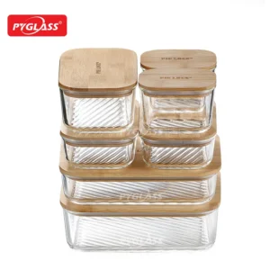 A set of glass storage containers with wooden lids stacked in various sizes, featuring the PYGLASS logo.