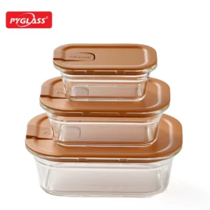 Three stackable glass food storage containers with brown lids, varying in sizes, placed on a white background.