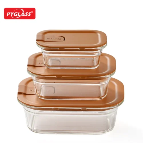 Three stackable glass food storage containers with brown lids, varying in sizes, placed on a white background.